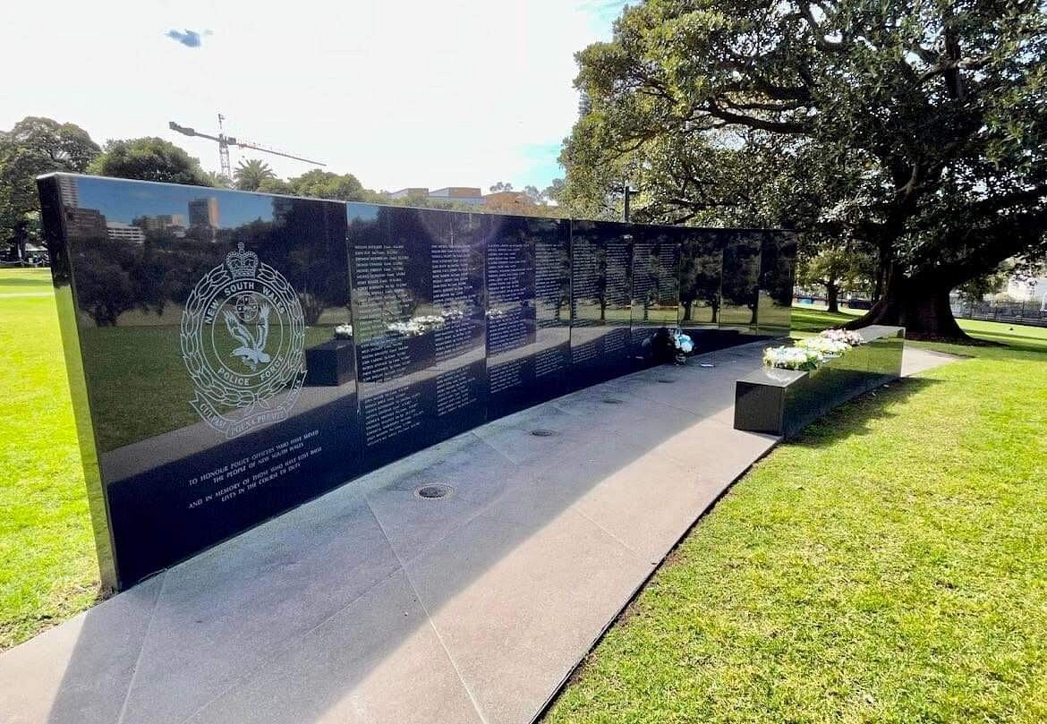 Polished black granite wall of remembrance for New South Wales Police, set in a park.